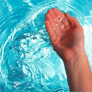 una mano tocando el agua con desinfectante con amonio cuaternario