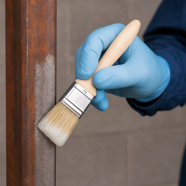 Persona aplicante el desoxidante fosfatizante en una estructura de metal